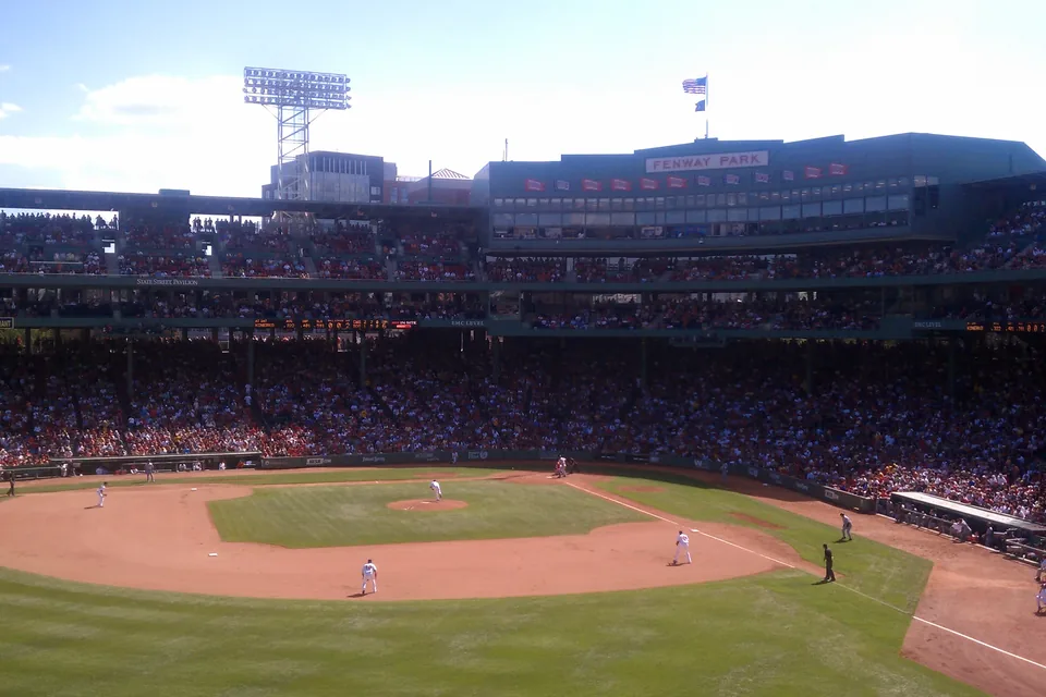Fenway Park from the stands on a sunny game day, the field and the Fenway Park sign in view.