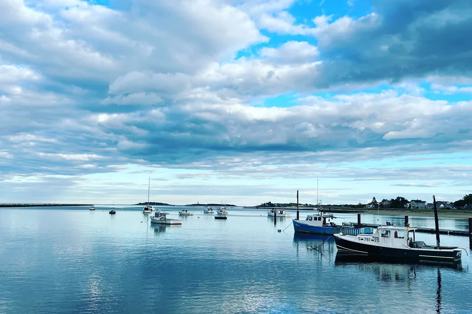 Fishing boats at their moorings on calm water under a broken blue sky at Camp Ellis, Saco.