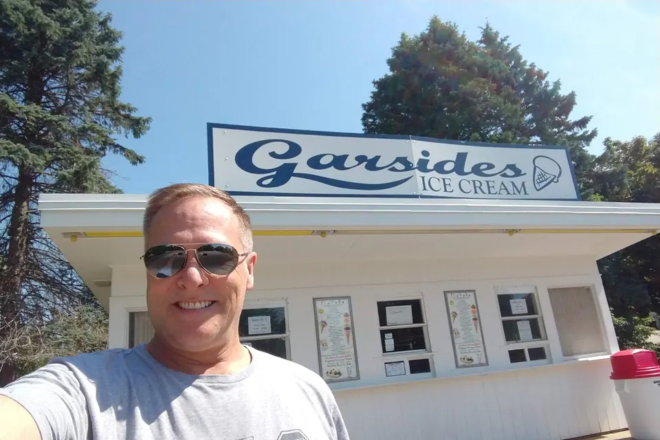 Eric in sunglasses in front of the Garside's Ice Cream stand and its sign.